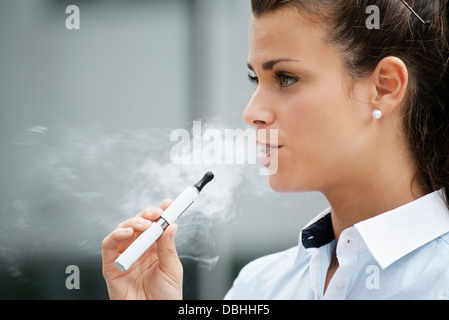 junge weibliche Raucher Rauchen e-Zigarette im Freien. Kopf und Schultern, Seitenansicht Stockfoto