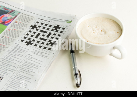 Der Zeitung The Times auf die kryptischen Kreuzworträtsels Seite mit einem Stift und einer Tasse Cappuccino Daneben öffnen. Stockfoto