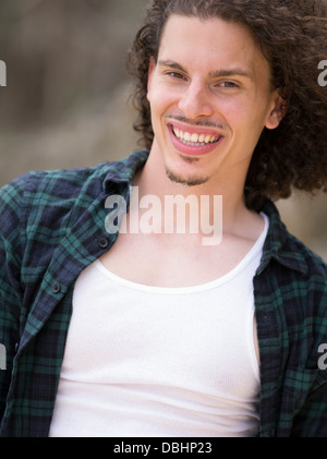 Ägyptischen amerikanischer Mann mit langem lockigem Haar Bart und Schnurrbart Lächeln auf den Lippen tragen check Shirt und weißes t-shirt Stockfoto