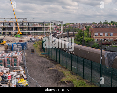 Ein Güterzug mit Kohle langsam bewegt sich zwischen einer kommerziellen Baustelle und ein Wohngebiet in York, Großbritannien. Stockfoto