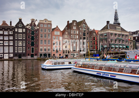 Hisitoric Häuser auf dem Wasser und Passagier Schiffe in Amsterdam, Holland, Niederlande. Stockfoto