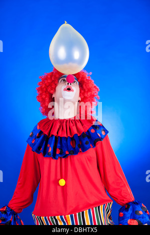 Lächelnden Clown im Studio gedreht auf blauem Hintergrund Stockfoto