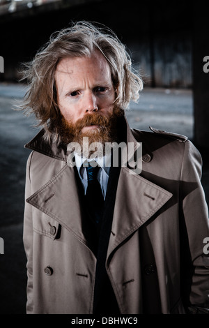 Bärtiger Mann in Anzug und Mantel in einer konkreten, urbane Umgebung. Stockfoto