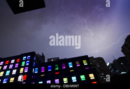 Blitze durchziehen den Himmel bei einem Gewitter in der Nacht, gesehen über den bunt beleuchteten Fenstern eines Designhotels im Chaoyang-Viertel von Peking, China. © Olli Geibel Stockfoto