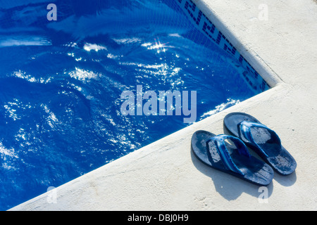 Ein paar Flip Flop Schuhe neben einem Schwimmbad. Stockfoto