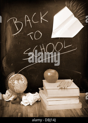 Zurück zur Schule geschrieben auf einer Tafel mit Büchern und Apfel in sepia Stockfoto