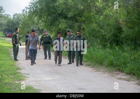 Border Patrol Agenten drei Einwanderer aus Mittelamerika zu eskortieren, nachdem ein van mit 26 auf einem Texas Highway abgestürzt Stockfoto