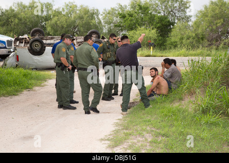 Border Patrol Agenten Frage Einwanderer aus Mittelamerika nach ein van mit 26 auf einem Texas Highway stürzte. Stockfoto