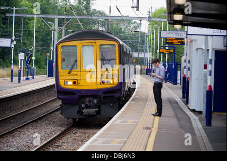 Ein Pendler auf der Plattform des Harpenden Bahnhof wie ein First Capital Connect-Zug zieht. Stockfoto