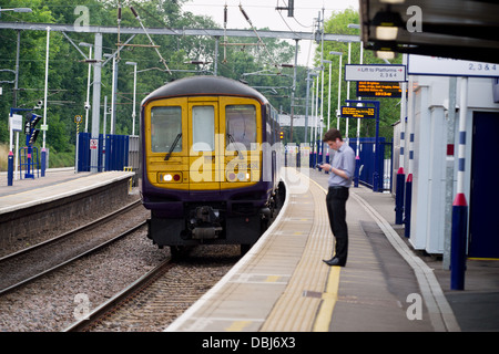 Ein Pendler auf der Plattform des Harpenden Bahnhof wie ein First Capital Connect-Zug zieht. Stockfoto