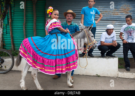 Ein junges Mädchen im hellen Tracht Lächeln beim Sitzen auf einem Esel auf Fiesta von Moyogalpa auf der Insel Ometepe Nicaragua Stockfoto