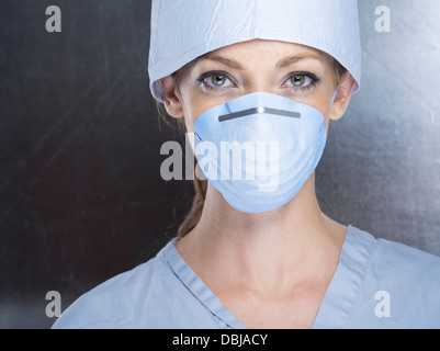 Weibliche Medic tragen scheuert sich chirurgische Kappe und Maske Stockfoto