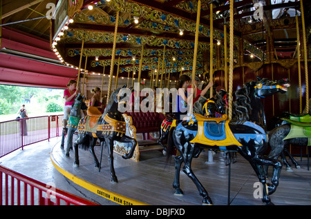 Kinder und Erwachsene genießen das Vintage Karussell fahren im Lakeside Park in St. Catharines, Ontario. Stockfoto