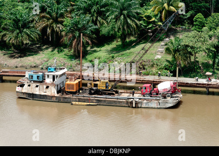 Lastkahn auf Kuching Fluss tragen Kräne und Betonmischer für den Ausbau der Riverside - pile driving Säulen ins Wasser. Stockfoto