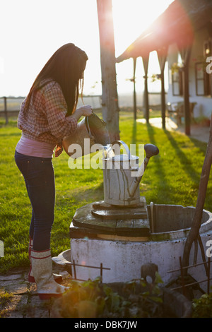 Junge Frau auf Bauernhof gießt Wasser in Eimer, Baranja, Kroatien, Europa Stockfoto