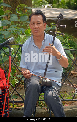 Chinesischer Mann spielen Erhu und Hereinholen Spenden im Columbus Park in Chinatown in New York City. Stockfoto