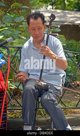 Chinesischer Mann spielen Erhu und Hereinholen Spenden im Columbus Park in Chinatown in New York City. Stockfoto