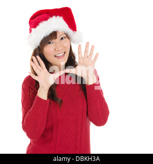 Fröhliche Weihnachten Frau aufgeregt sagen Hallo isoliert auf weißem Hintergrund tragen rote Weihnachtsmütze. Schöne asiatische Modell. Stockfoto