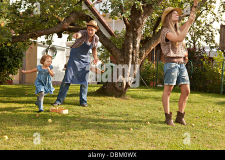 Eltern und Tochter pflücken Äpfel zusammen im Garten, München, Bayern, Deutschland Stockfoto