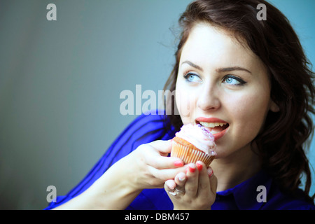 Frau mit braunen Haaren Essen einen Cupcake, Kopenhagen, Dänemark Stockfoto
