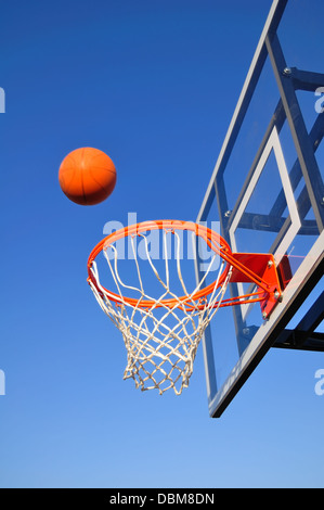Basketballkorb vor blauem Himmel wird ball geht ins Netz Stockfoto