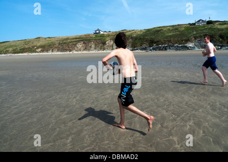 Jungen laufen und spielen mit einem rugby ball auf Whitesands Bay Beach Pembrokeshire Coast West Wales UK KATHY DEWITT Stockfoto