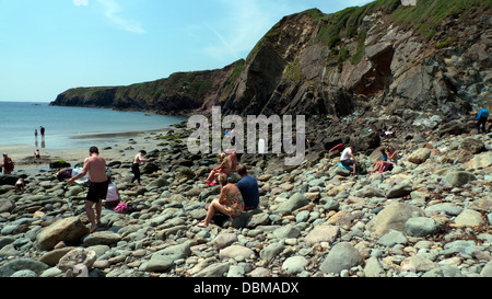 Leute sitzen auf den felsigen Strand bei Ebbe im Caerfai Bay im Sommer St. Davids Pembrokeshire Wales UK Stockfoto