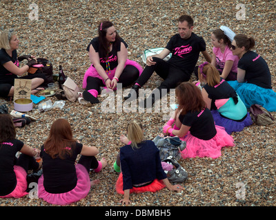 Ein Polterabend mit einem männlichen Freund sitzt am Strand von Brighton Stockfoto