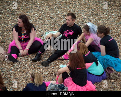 Ein Polterabend mit einem männlichen Freund sitzt am Strand von Brighton Stockfoto