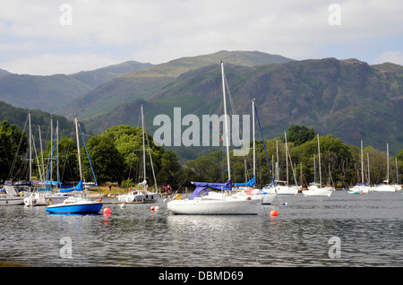 Segelboote vor Anker am Coniston Water neben Coniston Segelclub mit Seenplatte Bergen im Hintergrund. Stockfoto