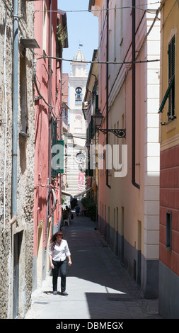 Frau entlang einer engen Straße in der historischen Stadt Albenga, Norditalien, Europa Stockfoto