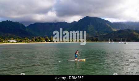 Stehen Sie Paddleboarder in Hanalei Bay auf Kauai bei Sonnenuntergang auf Stockfoto