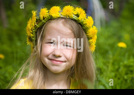 Closeup Portrait von lächelnden kleinen Mädchen in Löwenzahn Kranz auf grünen Rasen Hintergrund Stockfoto