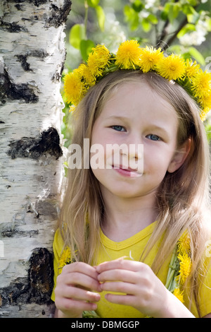 Closeup Portrait der lächelnde Mädchen im Löwenzahn Kranz stehen auf Birke Stamm Hintergrund Stockfoto