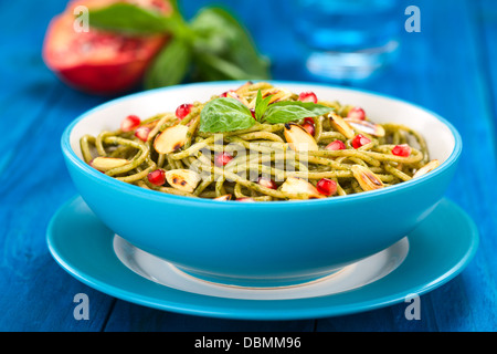 Spaghetti mit Pesto, Granatapfel und gerösteten Mandeln Hälften mit einem Blatt Basilikum garniert Stockfoto