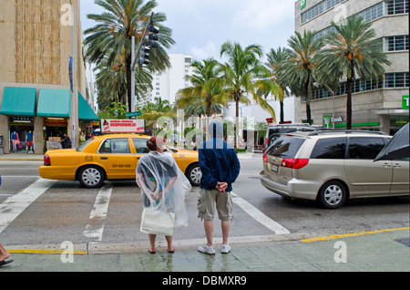 Zwei Besucher, South Beach, Miami, gekleidet für den regnerischen Tag auf ihrer shopping-Tour.  Bei starkem Regen Mitte Juli 2013. Stockfoto