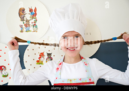 Kleines Mädchen mit Kochmütze herumalbern mit ihren Zöpfen, München, Bayern, Deutschland Stockfoto