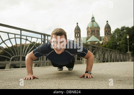 Junger Mann macht Liegestütze auf Brücke, München, Bayern, Deutschland Stockfoto