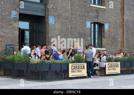 Wohnwagen Kings Cross, ist eine trendige Bar/Restaurant auf Granary Square, NC1, an einem warmen Sommertag, in London, UK am Abend Stockfoto