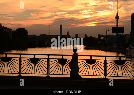 Berlin, Blick auf den Sonnenuntergang an der Spree von Oberbaumbrücke, mit Silhouette einer Frau und das Radio Turm im Hintergrund Stockfoto