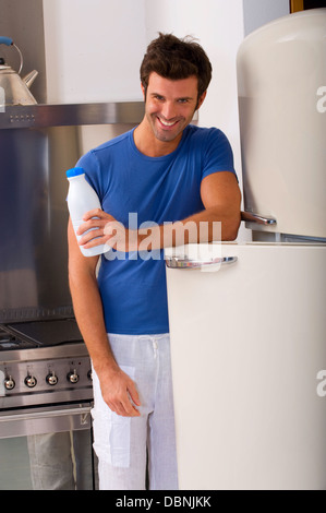 Mann in der Küche mit einer Flasche Milch Stockfoto