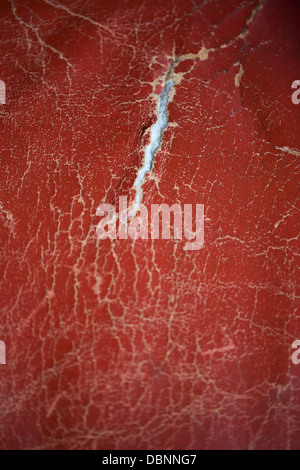 Rotes Leder getragen strukturiertem Hintergrund mit einer Träne im Gewebe Stockfoto