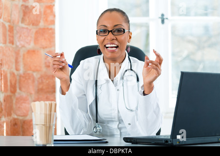 Junge schwarze Ärztin sitzen am Fenster in Klinik, sie hat ein Stethoskop Stockfoto