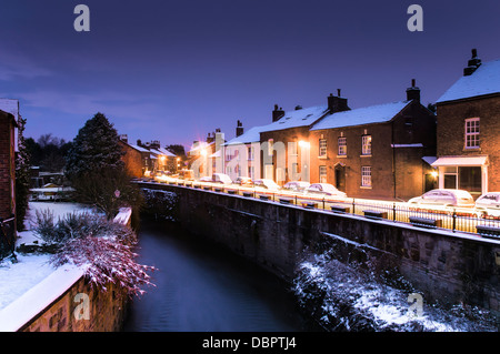 Ein Sonnenaufgang Bild auf einer verschneiten Croston Dorfzentrum, an Weihnachten während der Bremse & Scheinwerfer der vorbeifahrenden Fahrzeuge durch Streifen genommen. Stockfoto