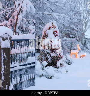 Eine frische fällt der Schnee deckt den Weihnachtsschmuck im Garten einen großen, eingezäunten Anwesen. Stockfoto