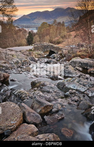 Eine herbstliche Ansicht der Ashness Brücke mit Blick in Richtung Derwent Water und Bassenthwaite Lake mit dem Skiddaw-Bereich im Hintergrund. Stockfoto