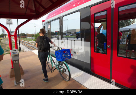 Weibliche Pendler verlässt einen Metro-Bahn-Zug mit ihrem Fahrrad an einer Haltestelle der öffentlichen Verkehrsmittel in Austin, Texas Stockfoto