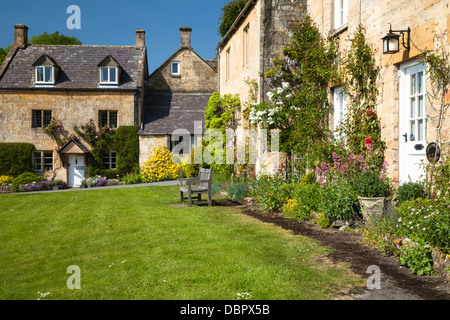 Honig-gesteinigt Cotswold Hütten mit Rosen und Sommerblumen, neben den Dorfanger in Stanton, Gloucestershire, England Stockfoto