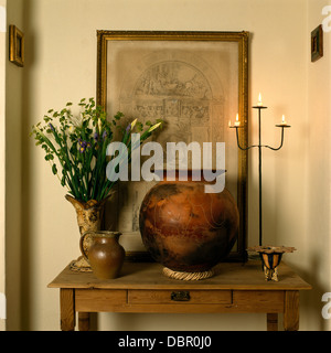 Nahaufnahme von großen Keramiktopf und schmiedeeiserne Leuchter auf Tischchen mit Vase mit Blumen und gerahmte Radierung Stockfoto