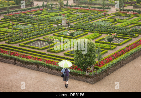 Einsame Gestalt unter einem Regenschirm in den Gärten des Chateau De Villandry, während ein sehr starker Regen-Dusche Stockfoto